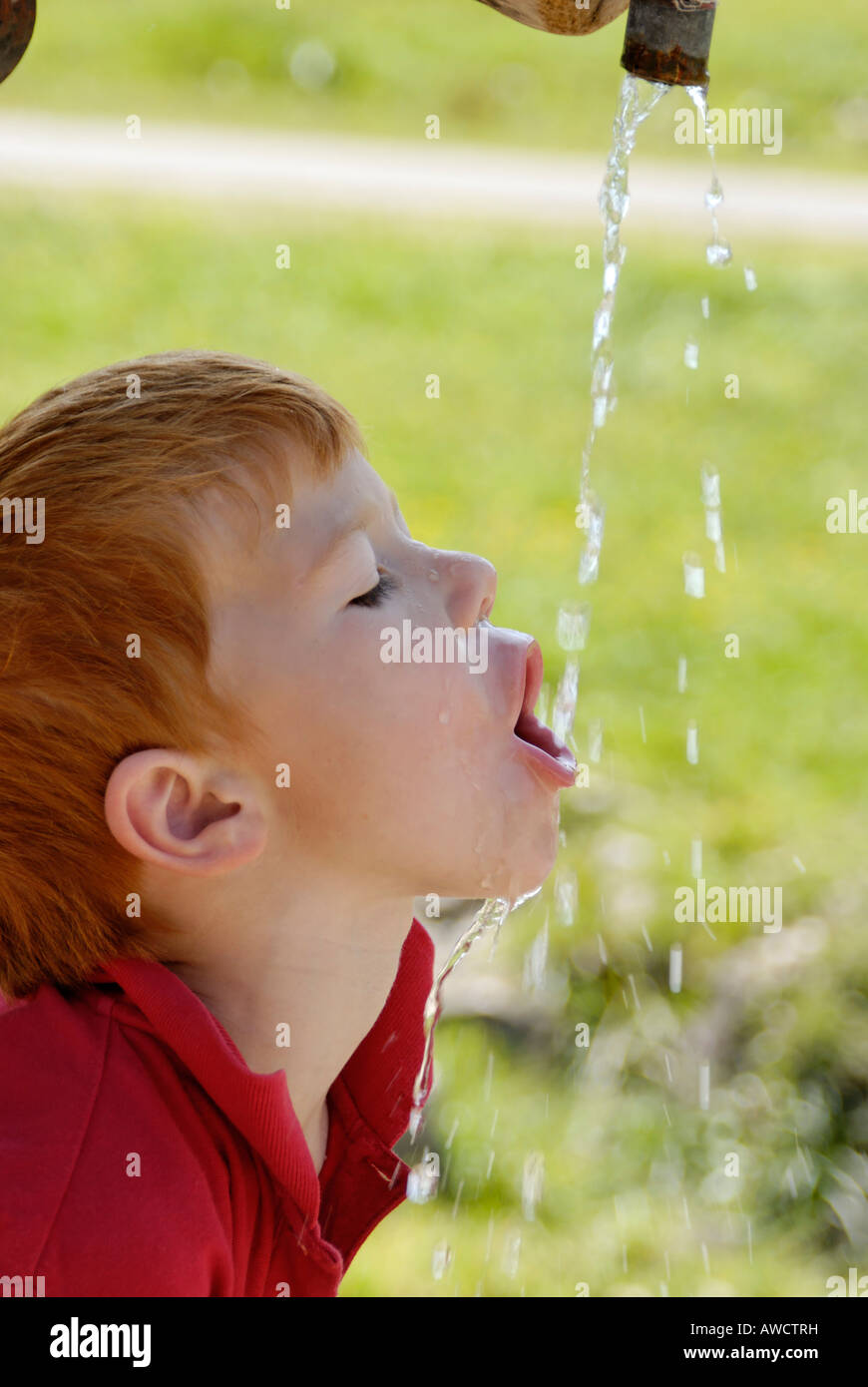 Bambino di bere acqua naturale da una fontana Foto Stock