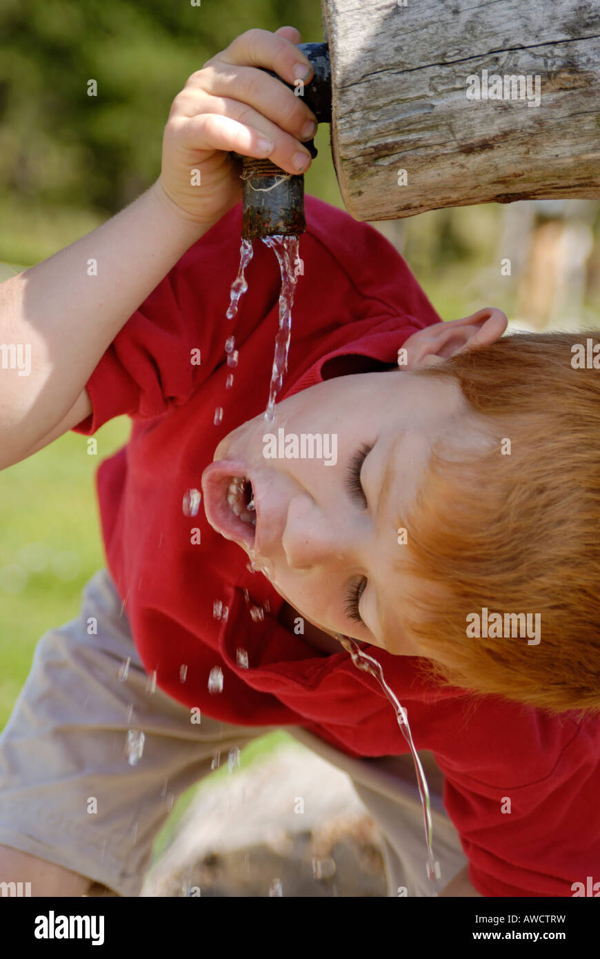 Bambino di bere acqua naturale da una fontana Foto Stock