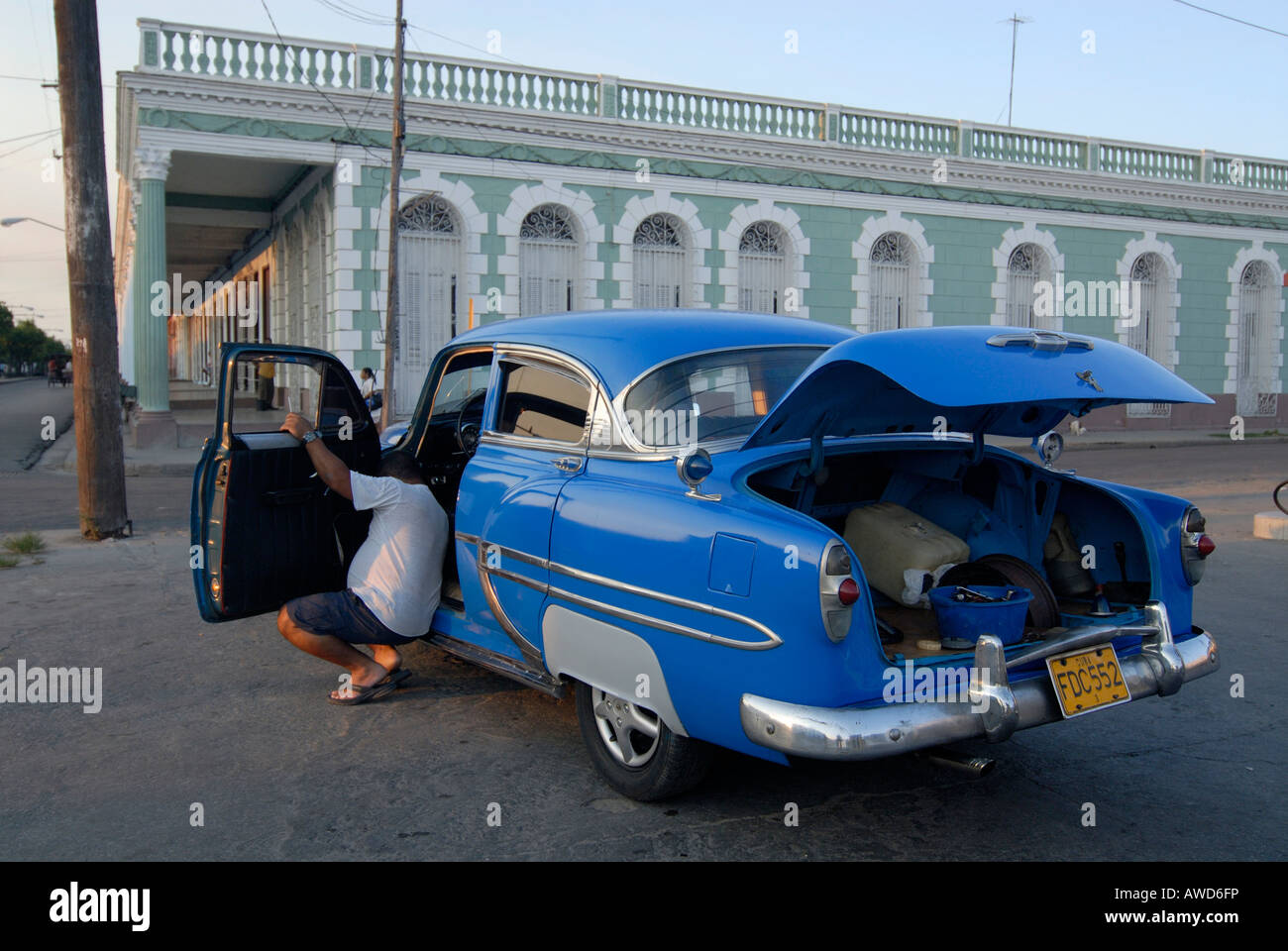 Auto d'epoca, sottoposti a riparazioni, il suo cofano sollevato, a fronte di un'era coloniale edificio a Cienfuegos, Cuba, Americhe Foto Stock