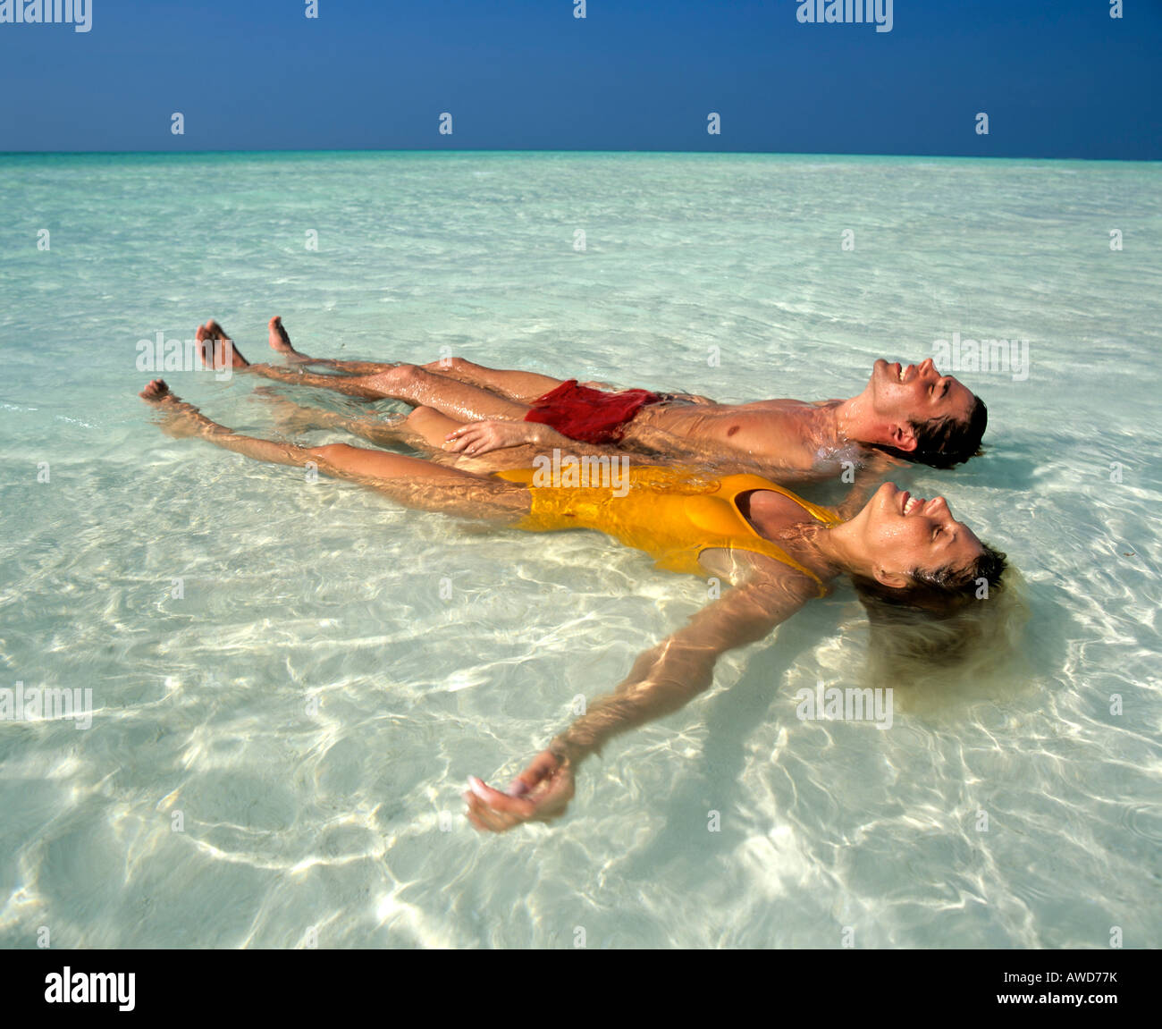 Coppia giovane rilassante in acque poco profonde, spiaggia, Maldive, Oceano Indiano Foto Stock