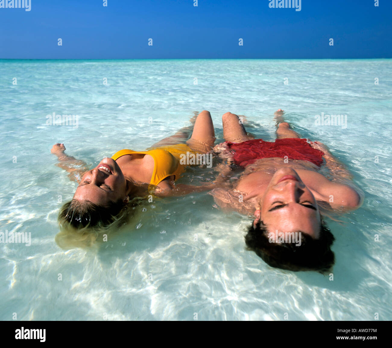 Coppia giovane rilassante in acque poco profonde, spiaggia, Maldive, Oceano Indiano Foto Stock