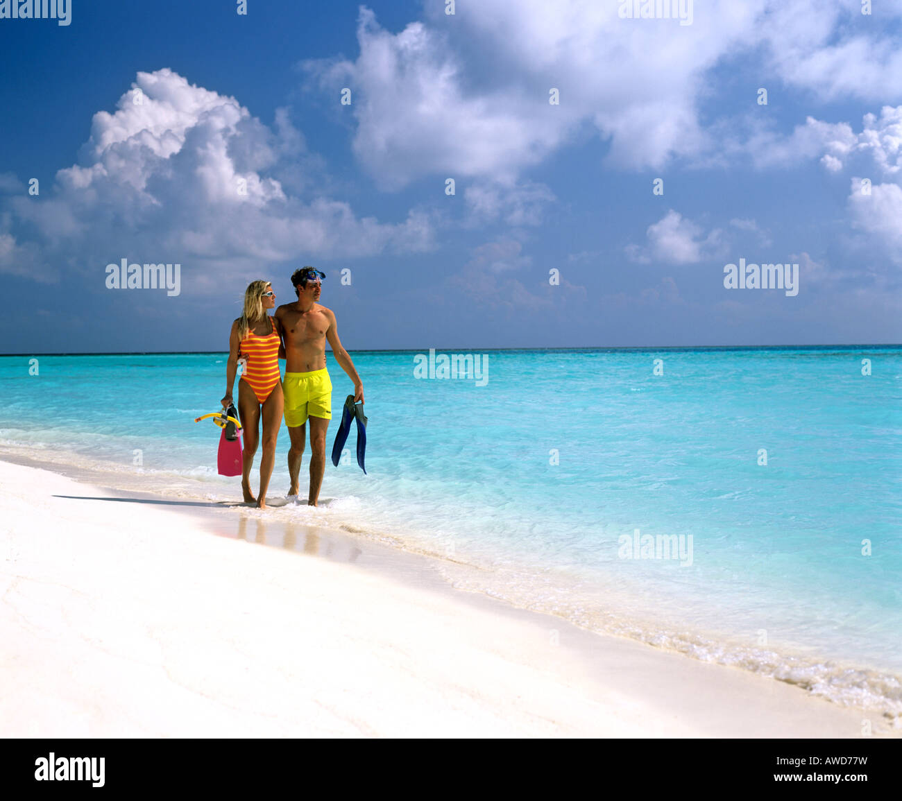 Coppia giovane con snorkeling a piedi in acqua poco profonda, spiaggia sabbiosa, Maldive, Oceano Indiano Foto Stock