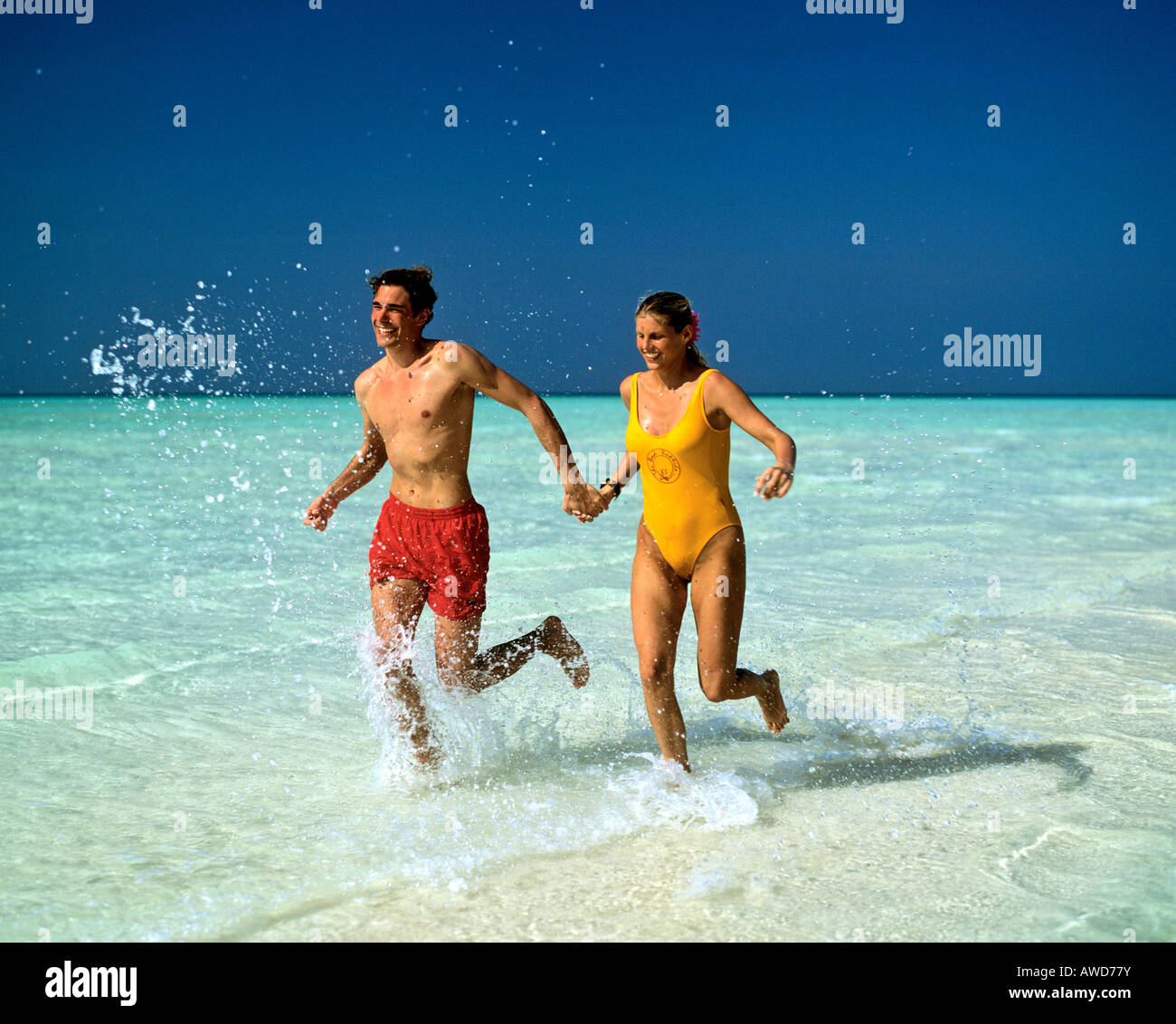 Coppia giovane jogging attraverso acque poco profonde, Maldive, Oceano Indiano Foto Stock