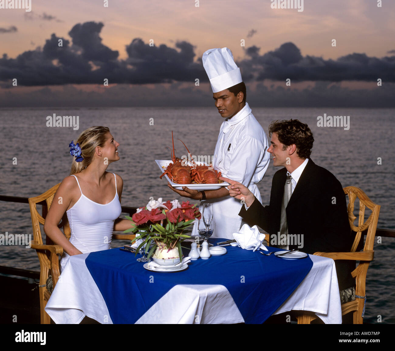 Coppia giovane al tramonto gustando una cena a base di aragosta, vacanza di lusso, Maldive, Oceano Indiano Foto Stock