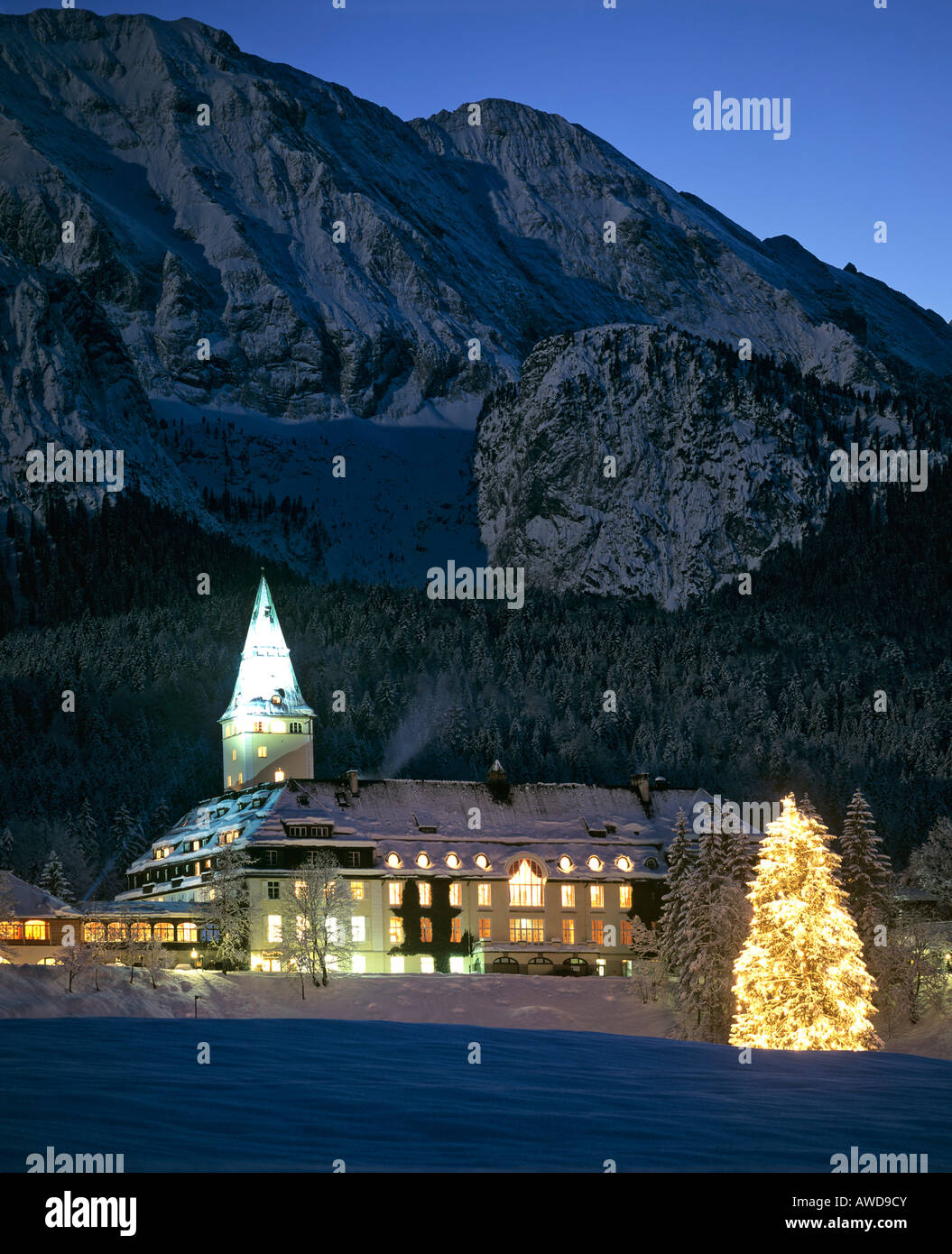 Il castello di Elmau nel crepuscolo con albero di natale, montagne del Wetterstein, Alta Baviera, Germania Foto Stock