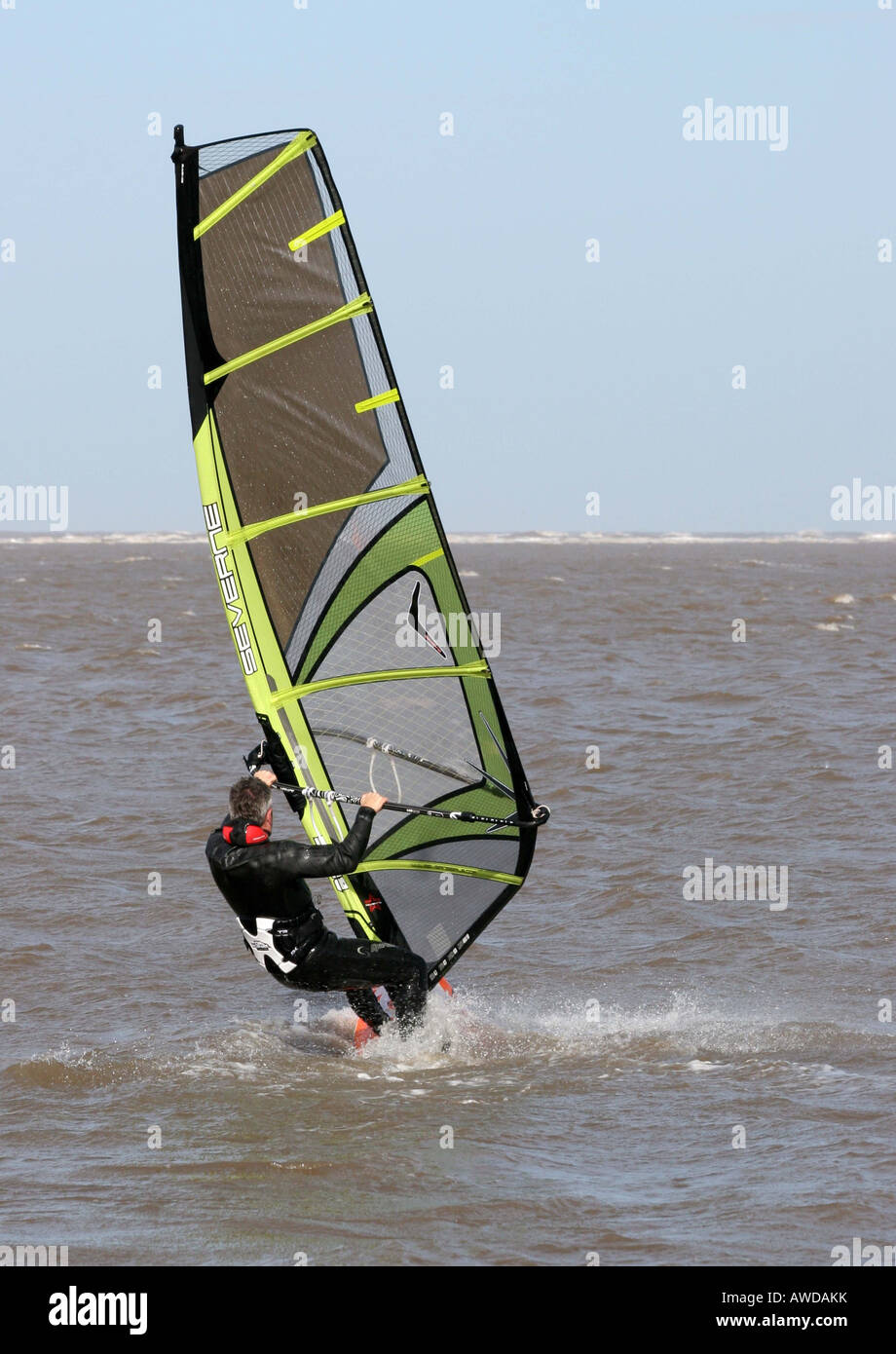 Windsurf con una vela verde racing sopra le onde Foto Stock
