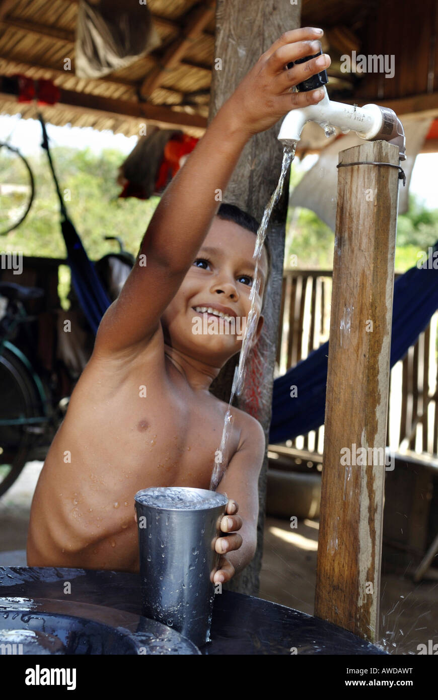 Ragazzo il riempimento di acqua in un abbeveratoio, bacino amazzonico, Brasile Foto Stock