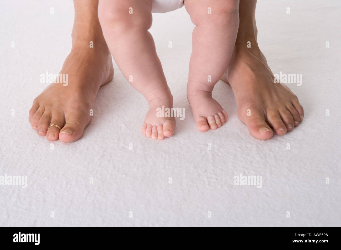 Due piedi del bambino con due piedi grandi Foto Stock
