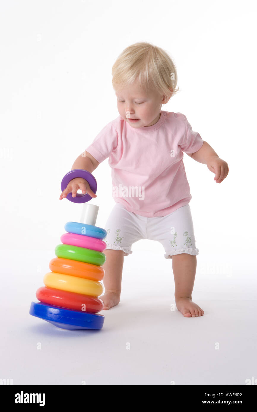 Bambina gioca sul pavimento con un giocattolo colorato anelli Foto Stock