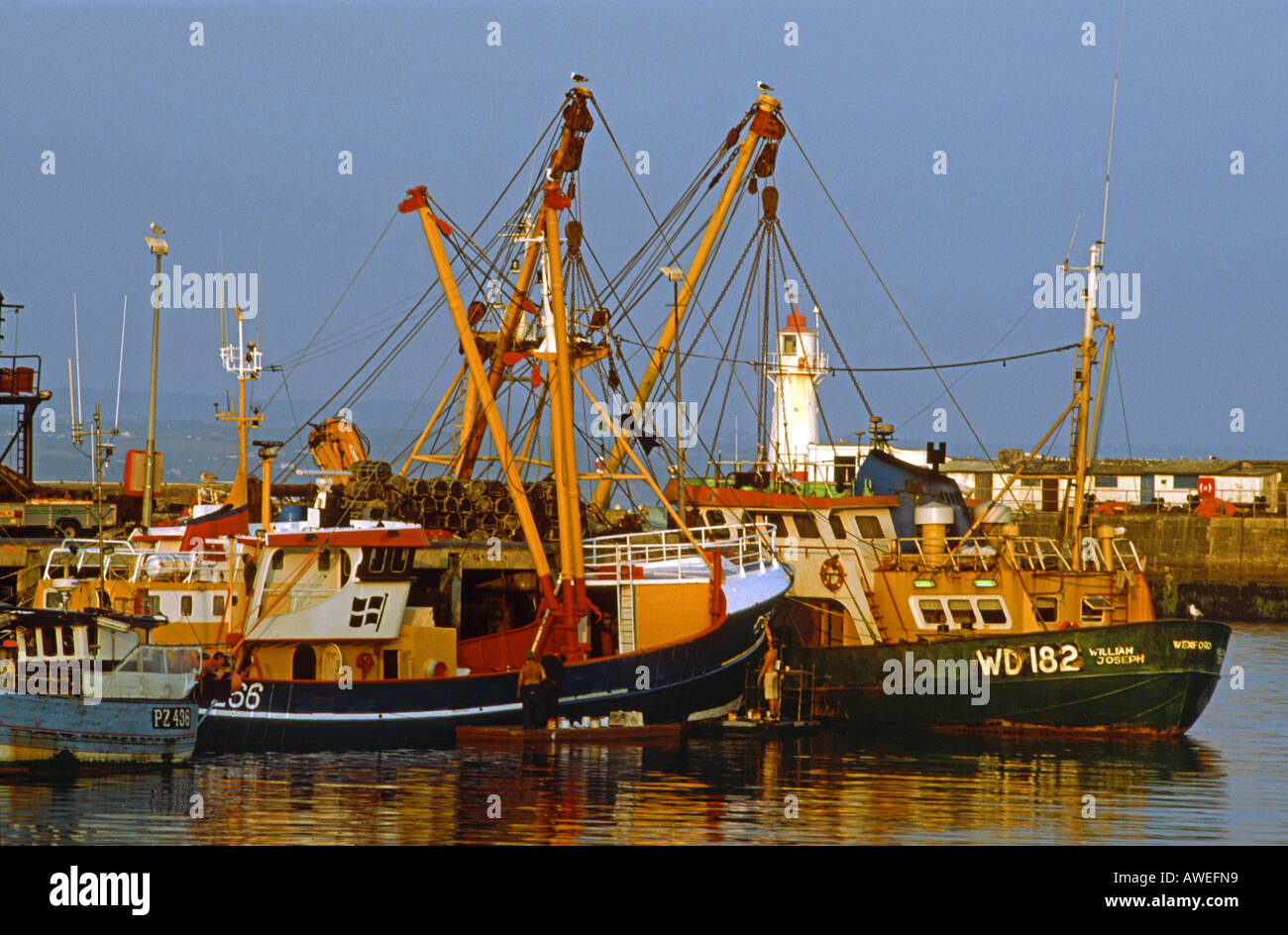 La pesca a strascico ormeggiata nel porto di Newlyn mentre la pittura è effettuata, Cornwall, Regno Unito Foto Stock