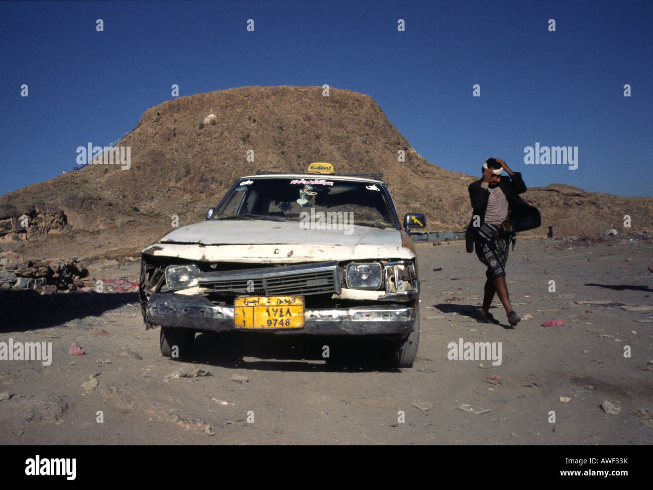 Un uomo si allontana dal suo picchiati vecchio taxi di fronte al vulcano di Hamman Damt Foto Stock