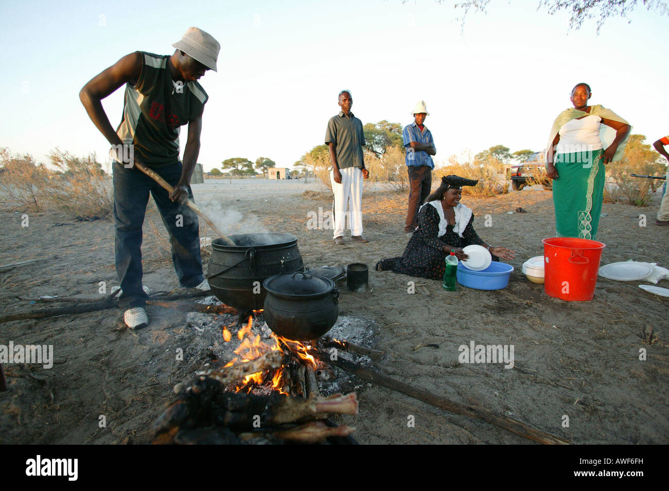Gli uomini la cottura nella piazza del villaggio, Sehitwa, Botswana, Africa Foto Stock