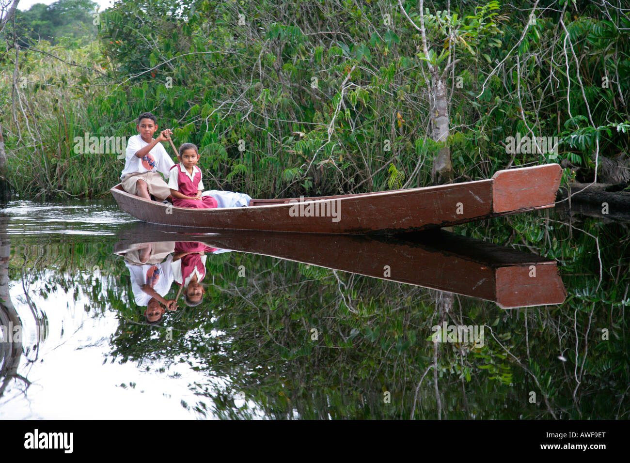 Ragazzo di prelevare la sua sorella più giovane dalla scuola con la sua barca, indigeni Arawak, Santa Missione, Guyana, Sud America Foto Stock