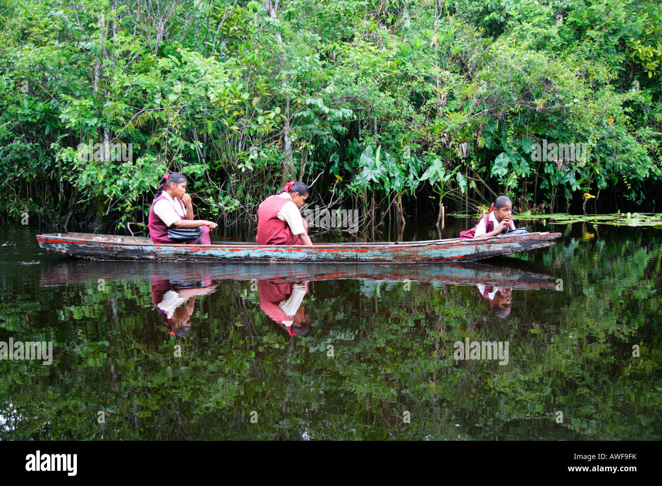 Ragazza che indossano uniformi scolastiche in una barca sul suo modo a casa da scuola, indigeni Arawak, Santa Missione, Guyana, Sud America Foto Stock