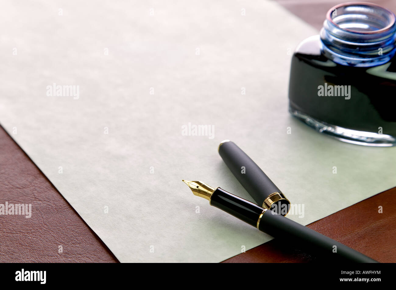 Oro nibbed penna stilografica marchiata carta costosa e un inkwell su una scrivania in pelle top Foto Stock