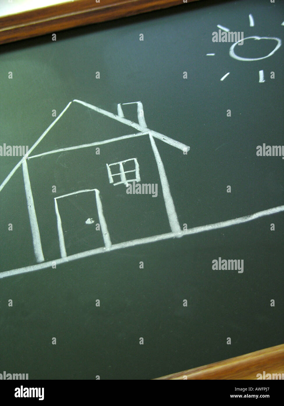 Bambino su disegno di una casa e il sole su una lavagna. Foto Stock