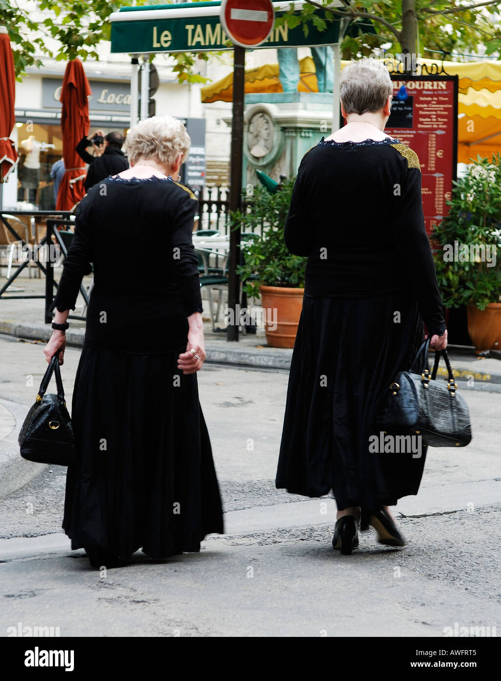 Due anziane signore analogamente vestita di nero attraversare a piedi Place du Forum ad Arles, Provenza, Francia Foto Stock