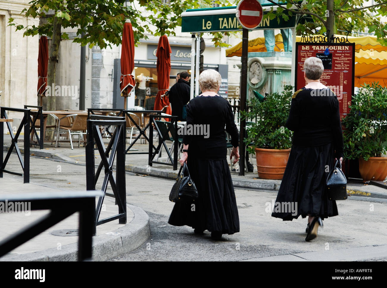 Due anziane signore analogamente vestita di nero attraversare a piedi Place du Forum ad Arles, Provenza, Francia Foto Stock