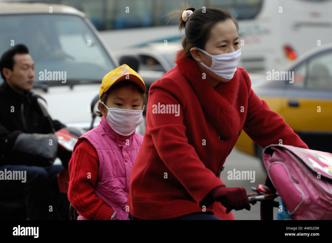 Madre e figlia che indossa la maschera mentre bike a scuola a Pechino, uno dei più aria inquinata città in tutto il mondo.12-Mar-2008 Foto Stock