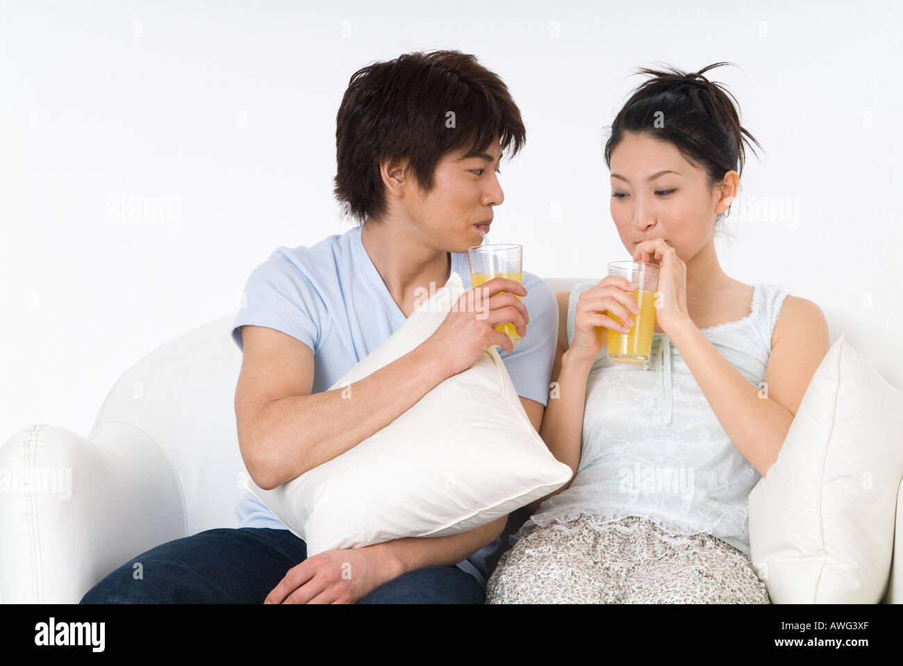 Coppia giovane seduto sul divano e bere il succo d'arancia Foto Stock
