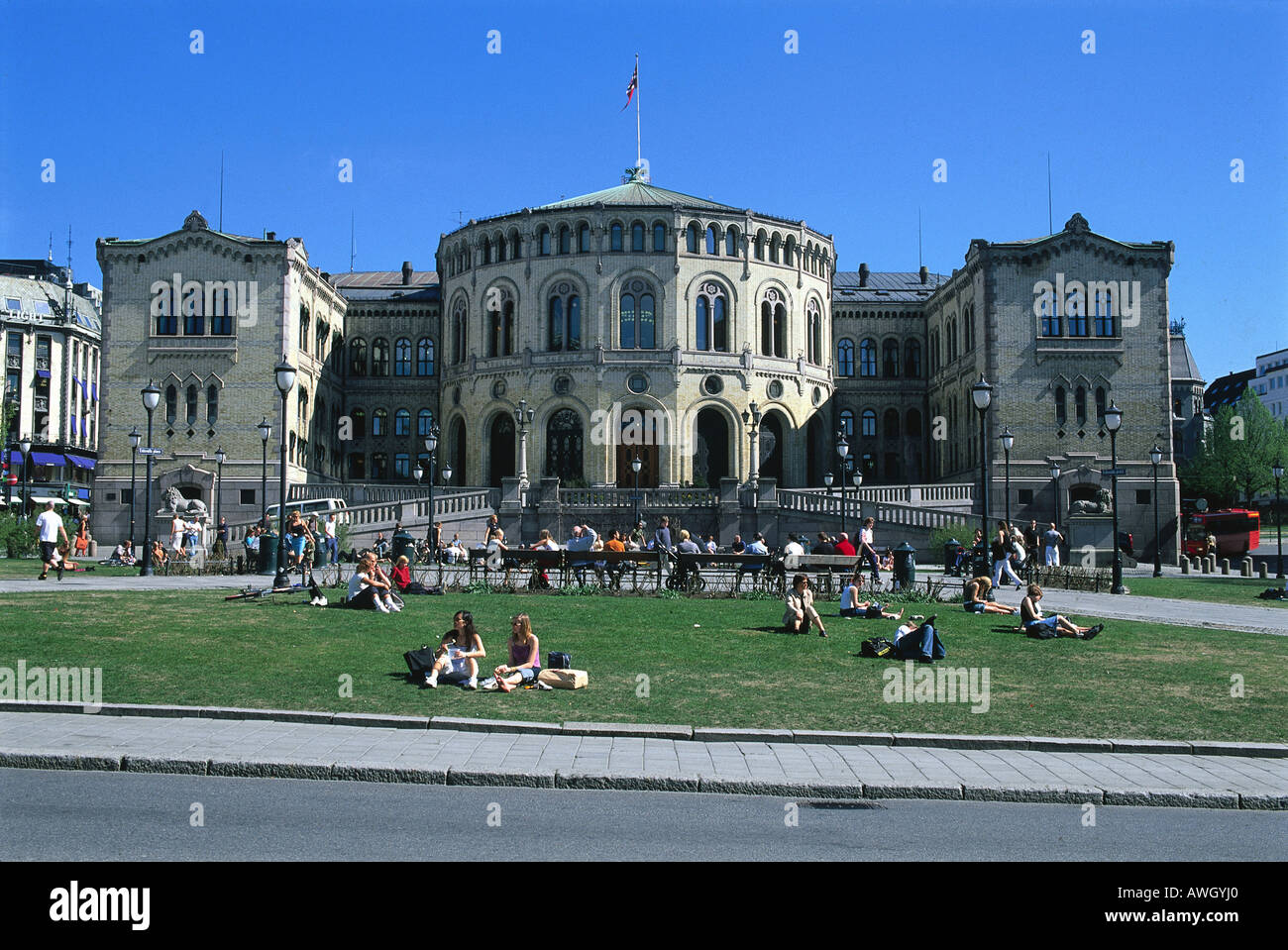 Norvegia, Oslo, Stortinget, gente seduta in motivi, facciata del palazzo del parlamento, costruito del mattone giallo rossastro sulla base di granito Foto Stock