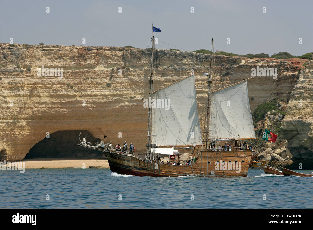 Una riproduzione portoghese di una caravella l vele passato spiagge grotte e scogliere lungo la costa di Algarve in Portogallo. Foto Stock