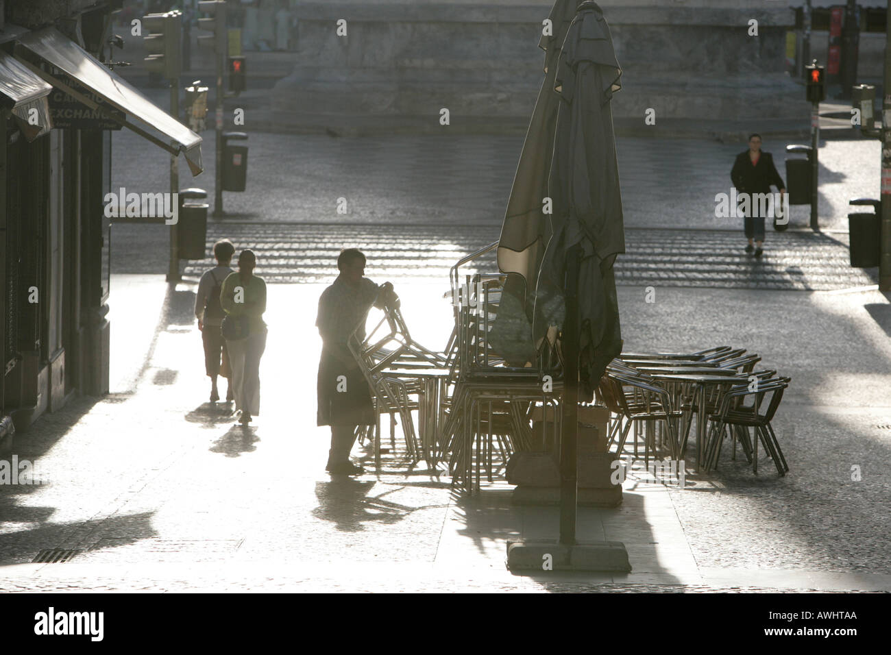 Un cafe proprietario viene tabelle pronti per un nuovo giorno a Lisbona Portogallo. Foto Stock