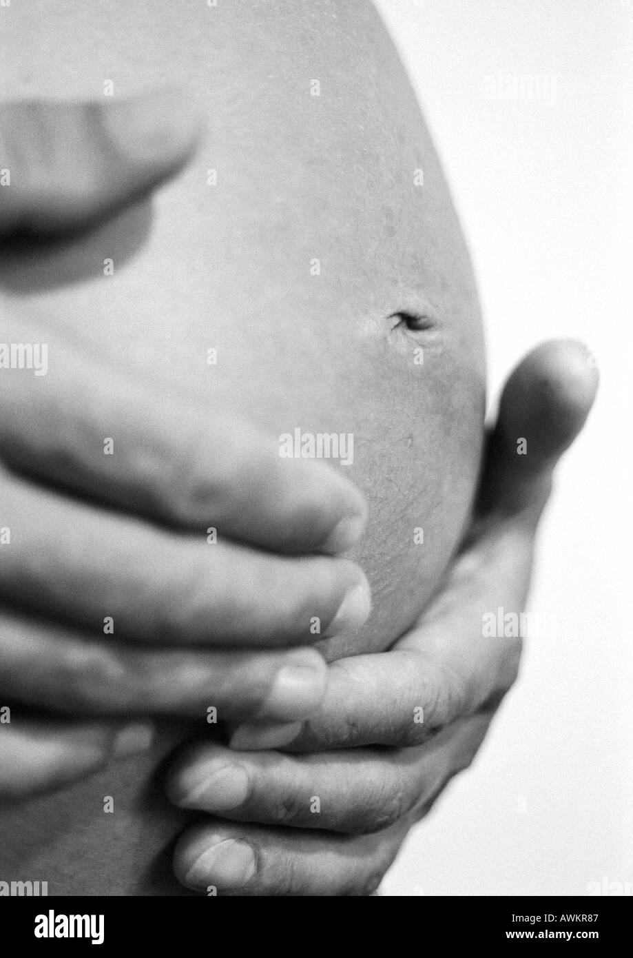 Mani sulla donna incinta il ventre, b&W Foto Stock
