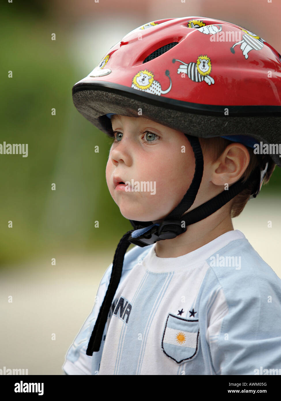 Piccolo ragazzo che indossa il casco per bicicletta e sport shirt con uno sguardo contemplativo sul suo volto Foto Stock