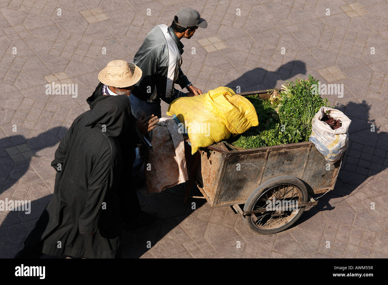 Gli uomini spingendo il carrello caricato con materie vegetali verdi e sacchi, Djemaa el Fna a Marrakech, Marocco, Africa Foto Stock