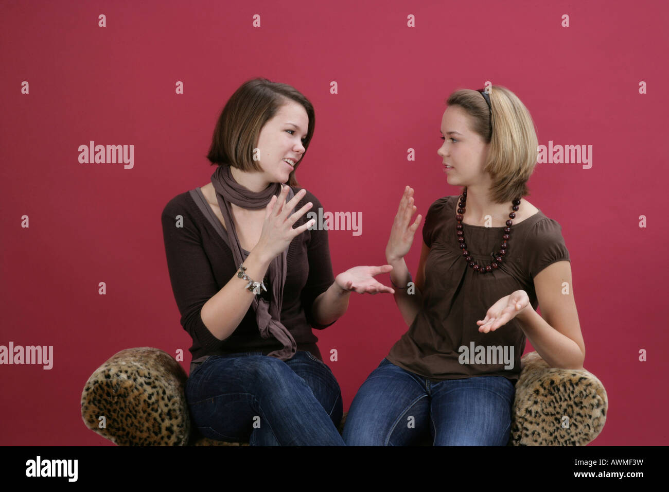 Due ragazze, pre-adolescenti, dai primi anni dell'adolescenza seduto su una tigre-stampa parla del lettino Foto Stock