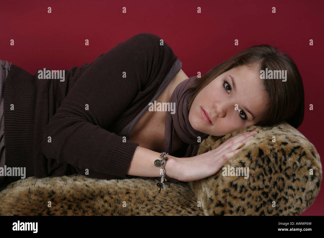 Ritratto di una ragazza, pre-teen, early teens posa su un tiger-divano di stampa Foto Stock