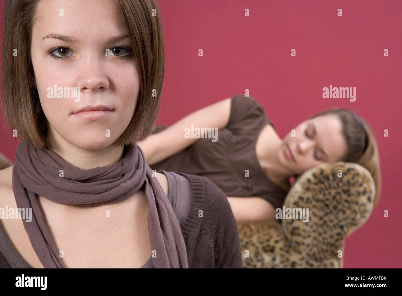 Due ragazze, pre-adolescenti, dai primi anni dell'adolescenza, uno di dormire su una tigre divano stampa con gli altri in primo piano Foto Stock