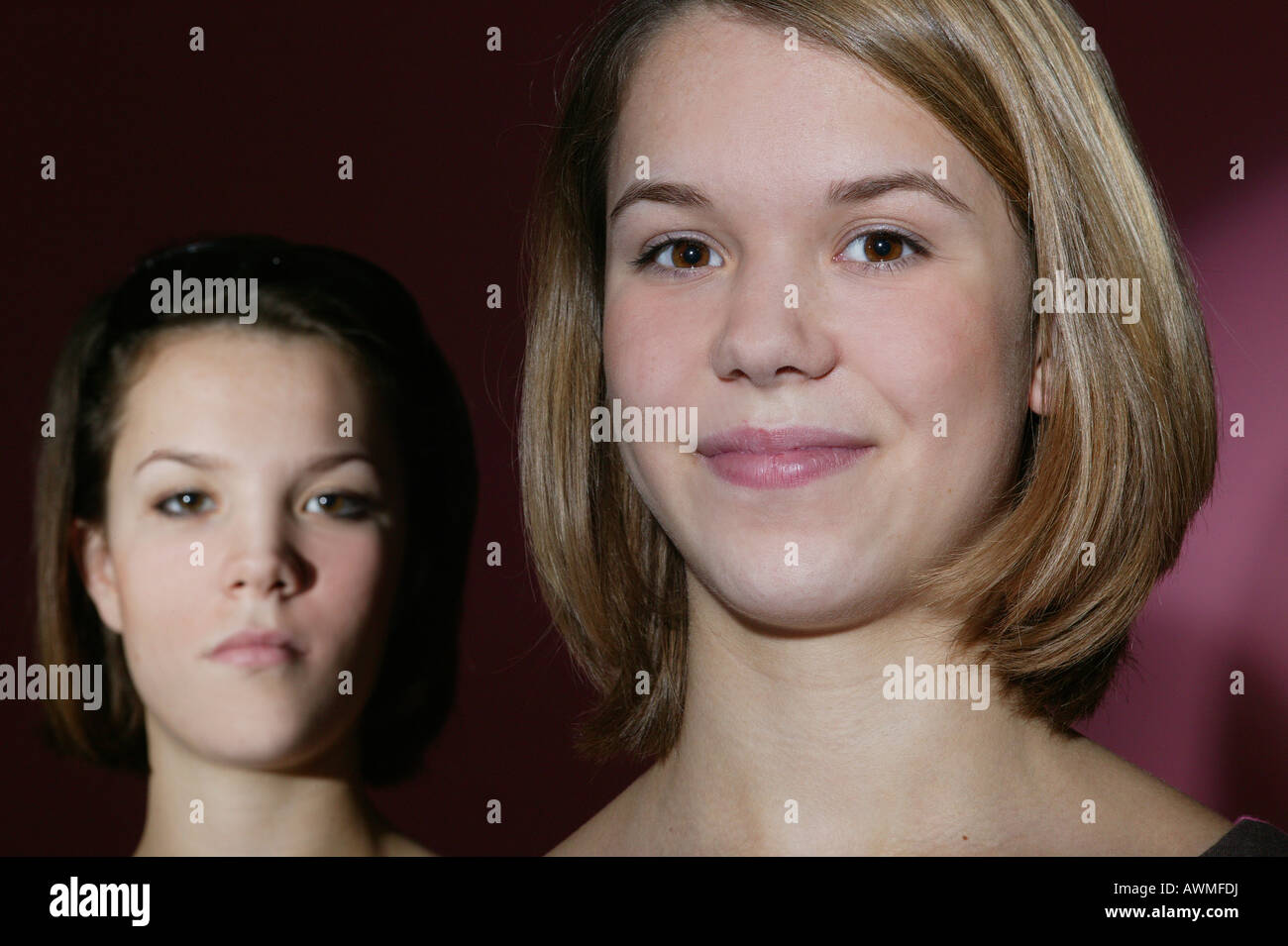 Due ragazze, pre-teen, dai primi anni dell'adolescenza, un sorridente altri cercando gravi Foto Stock