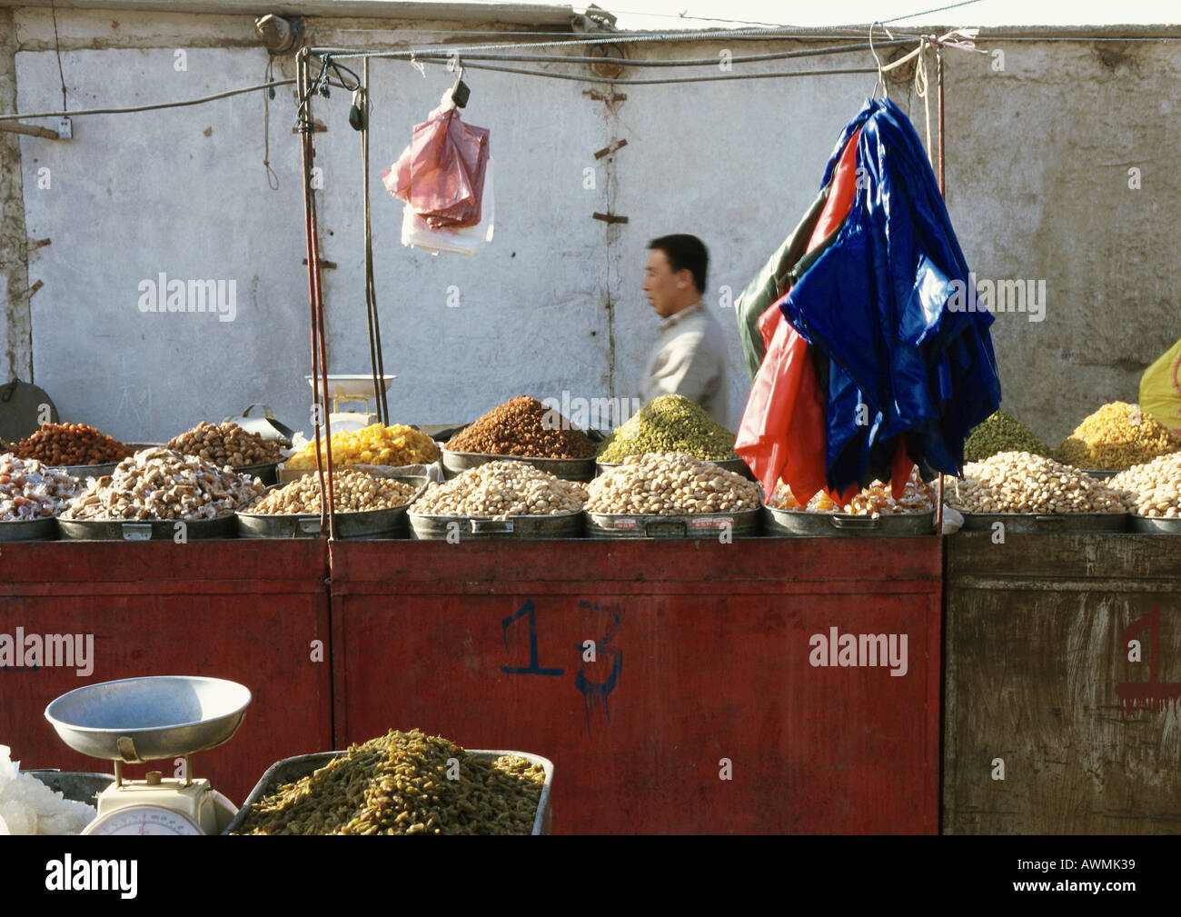 Cina, Xinjiang, Turpan, uomo dietro pressione di stallo nel mercato all'aperto Foto Stock