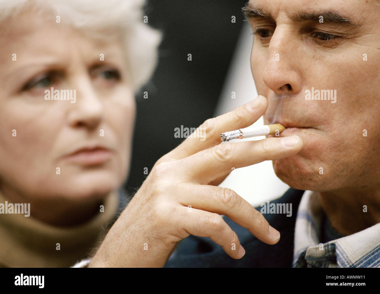 Uomo di fumare, donna sfocati sullo sfondo, close-up Foto Stock