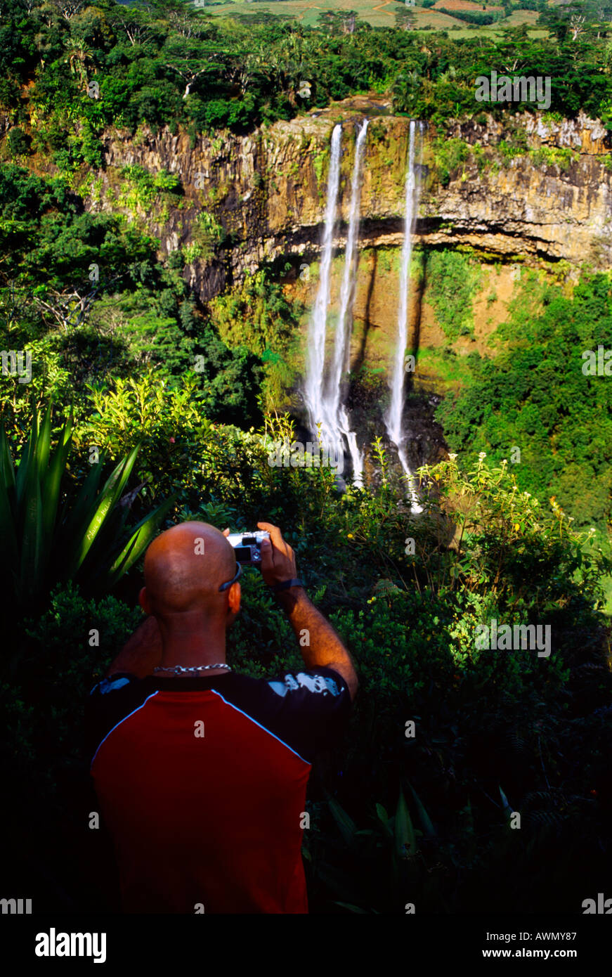 Chamarel Waterfall Mauritius Bald Capeggiato uomo fotografando con fotocamera digitale-cascate formate dal fiume St Denis e circondato dalla vegetazione di Foto Stock