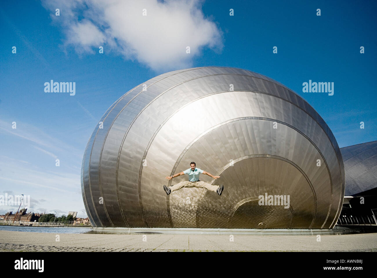 L'uomo jumping davanti a Glasgow Science Centre Foto Stock