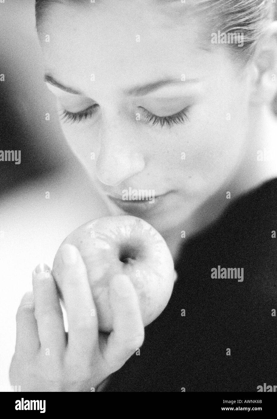 Donna che mantiene apple, guardando verso il basso, close-up, B&W. Foto Stock