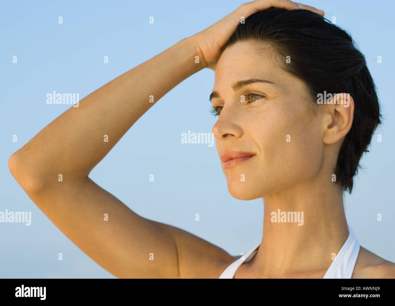 Donna con la mano sulla testa, sorridente Foto Stock