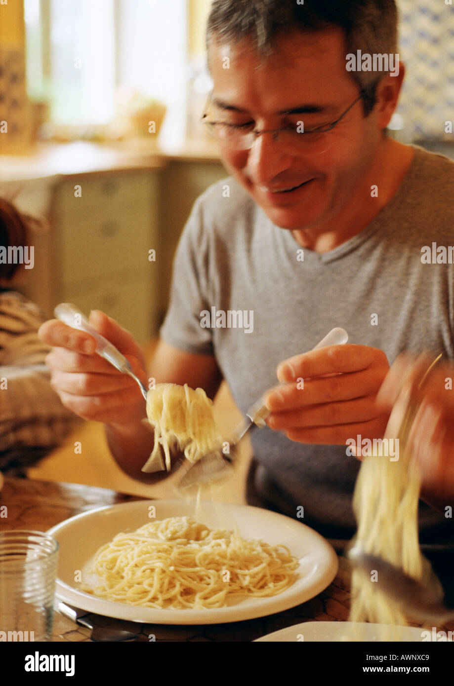 L'uomo mangiare spaghetti con cucchiaio e forchetta, movimento sfocato Foto  stock - Alamy