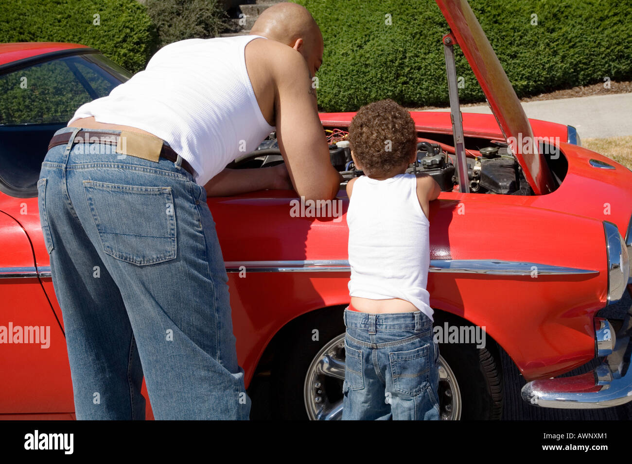 Padre e figlio esaminando sotto cappa per auto Foto Stock