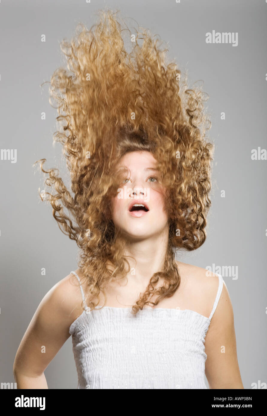 Giovane donna, i suoi lunghi capelli ricci volare attraverso l'aria Foto Stock