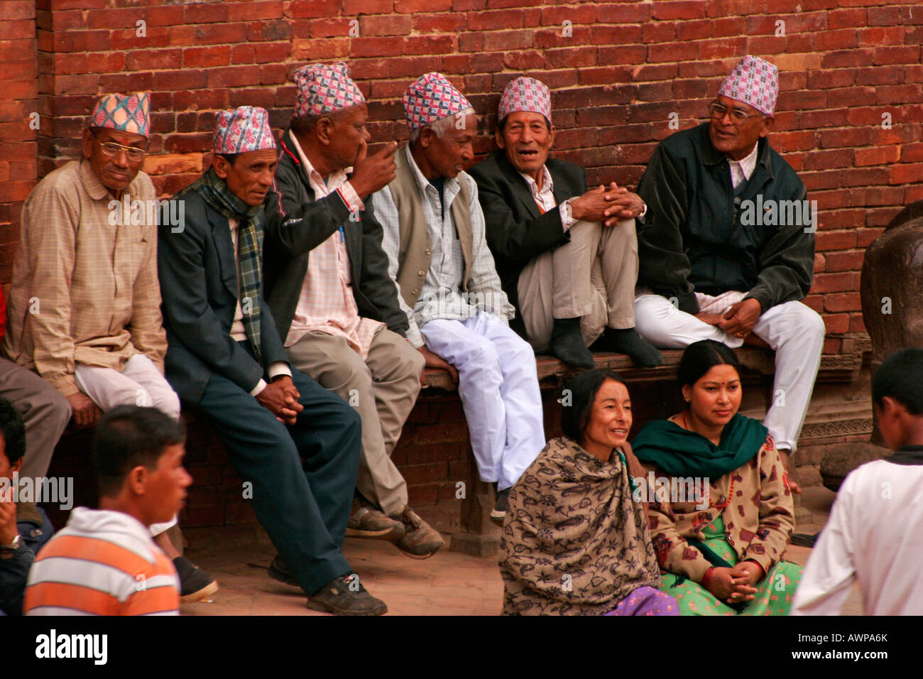 Sei anziani signori indossando tipico Nepalese rivestimenti di testa denominata " topi' seduta su una panchina in chat, Patan in Kathmandu Foto Stock