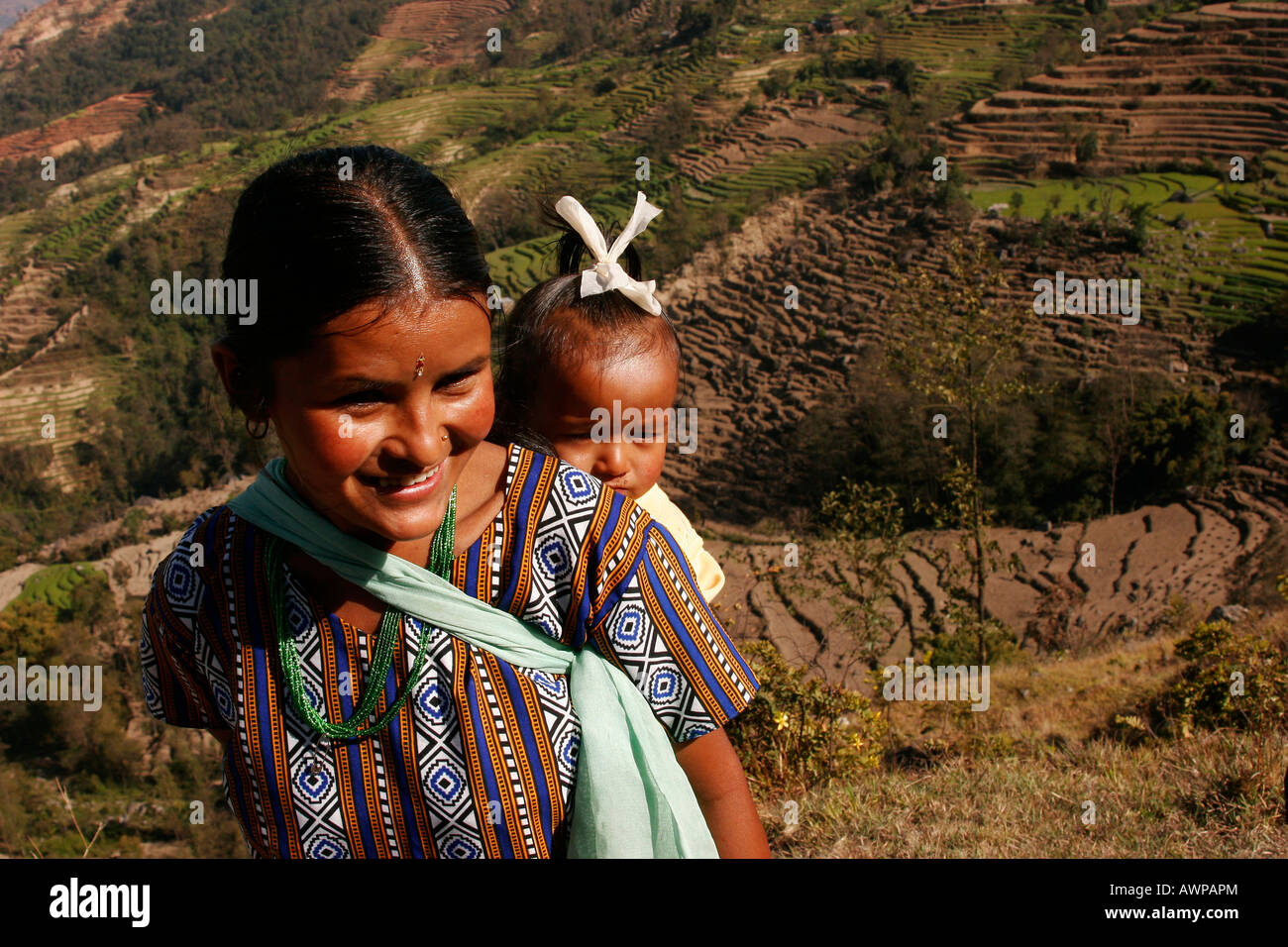 Una giovane madre che porta il suo bambino in una imbracatura sulla sua schiena, Nagarkot, Nepal, Asia Foto Stock