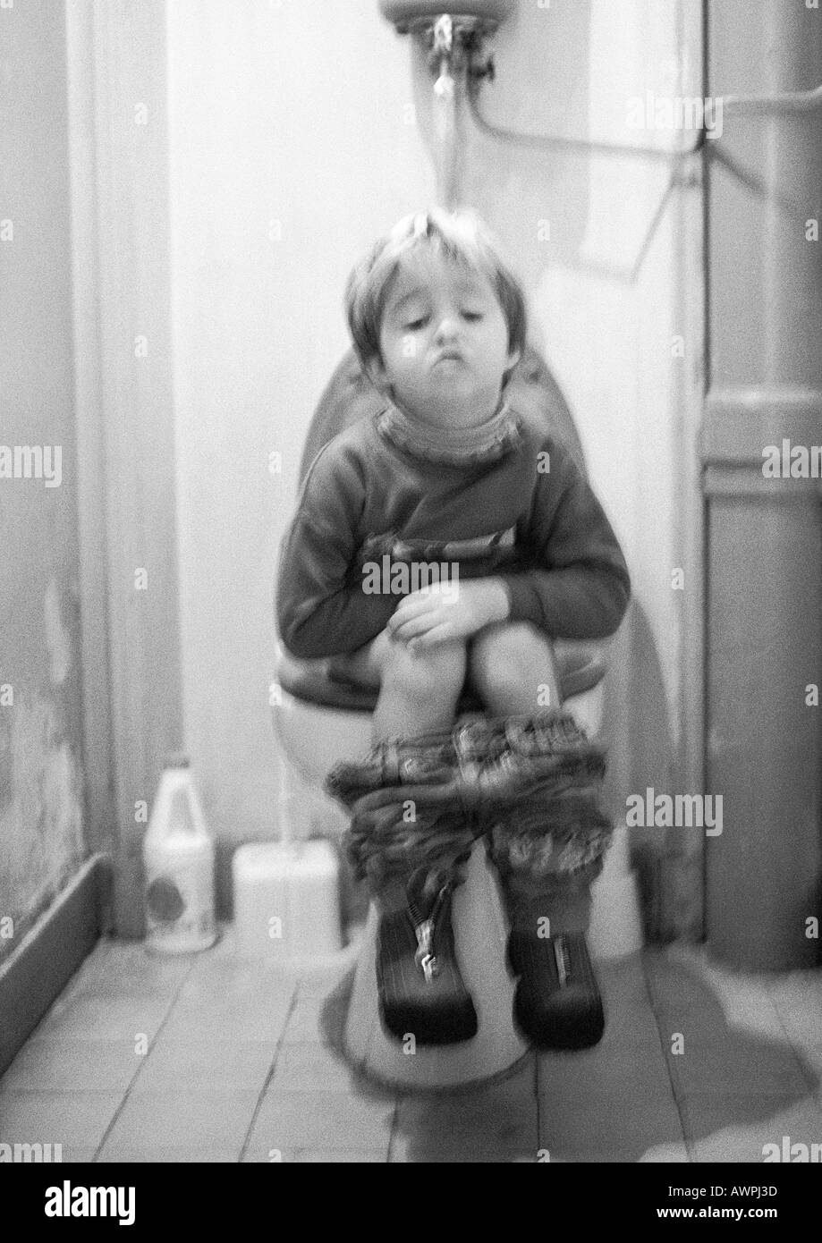 Poco ragazza seduta sul wc, b&W Foto Stock