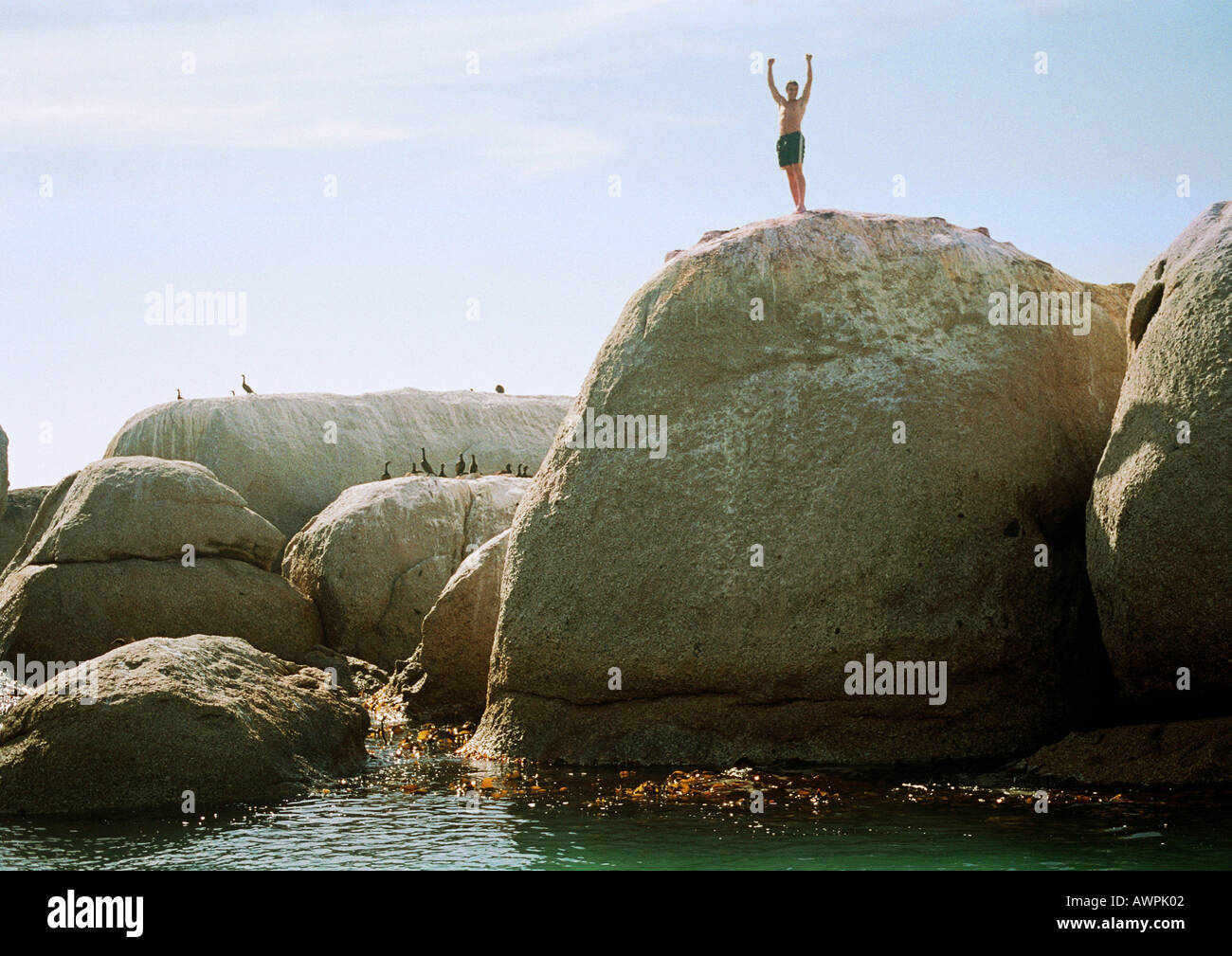 Uomo in piedi sulla roccia affacciato sul mare Foto Stock