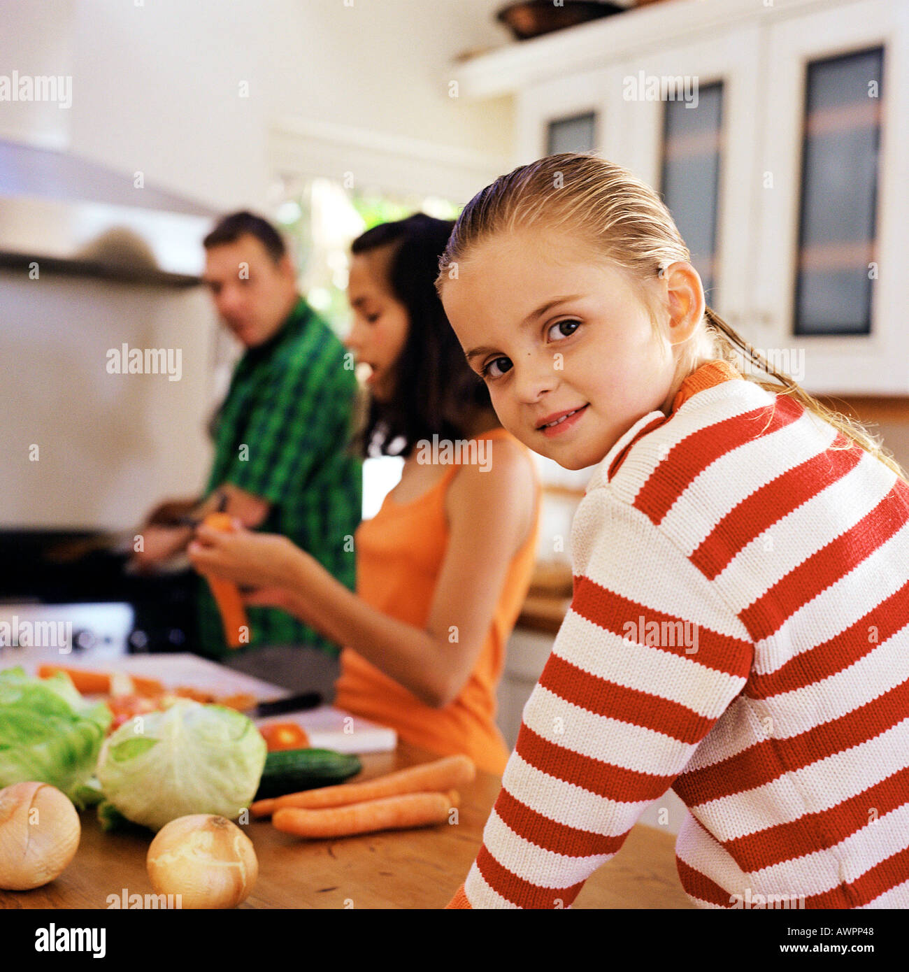 Cucina di famiglia, bambina guardando sopra la spalla Foto Stock