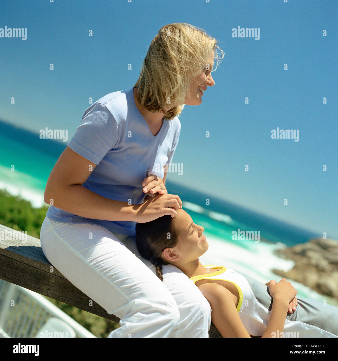 Ragazza con testa sulla madre di giro, mare in background Foto Stock