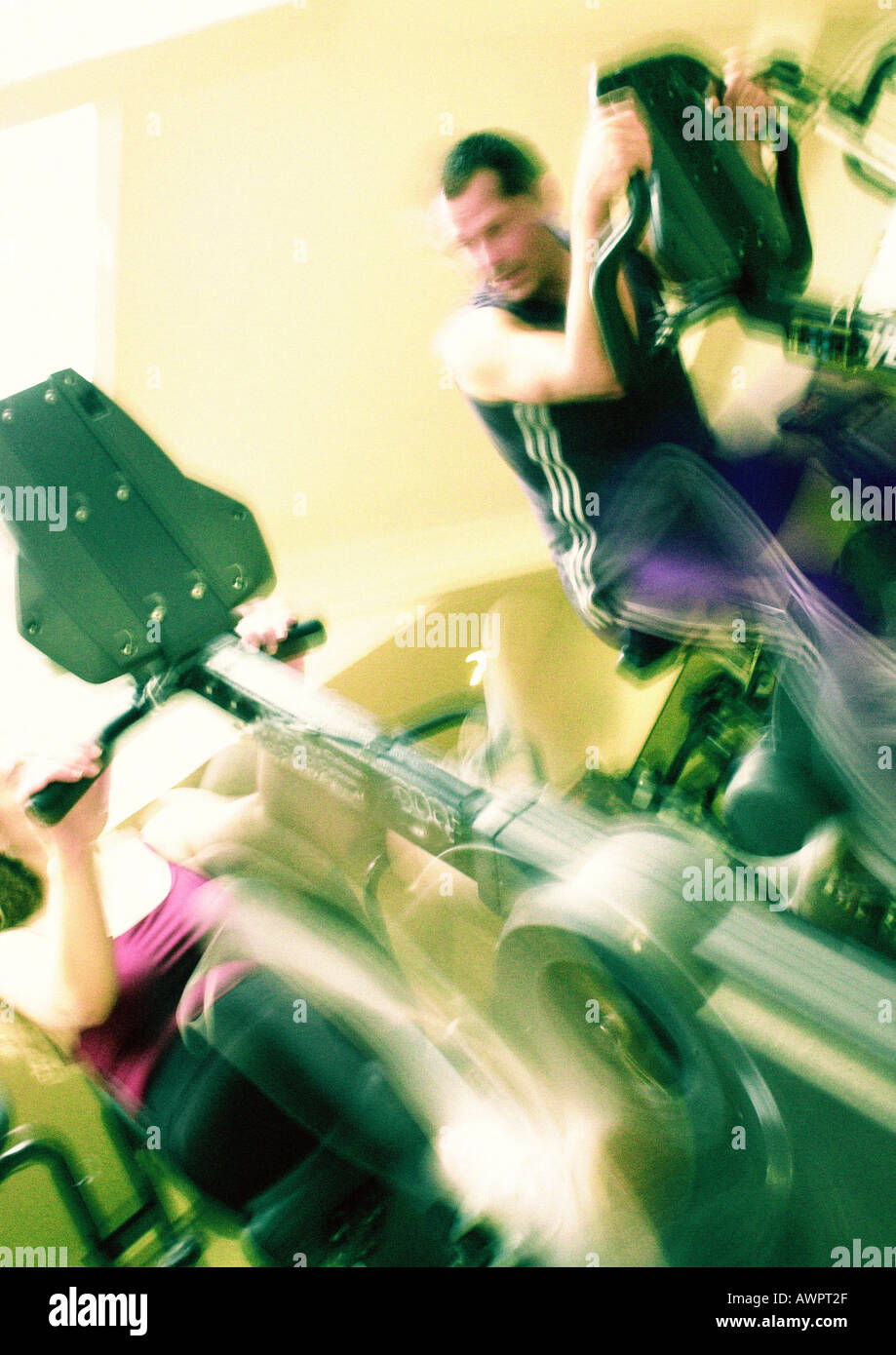 L uomo e la donna con cyclette in palestra, movimento sfocato Foto Stock